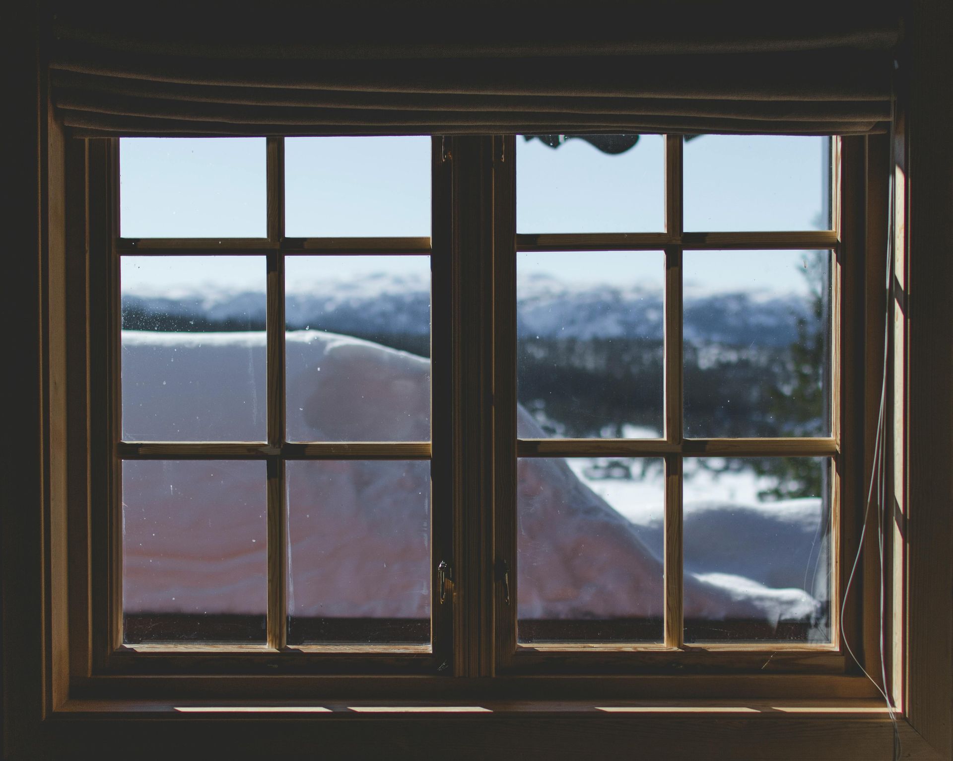 a window with a view of a snowy mountain range .