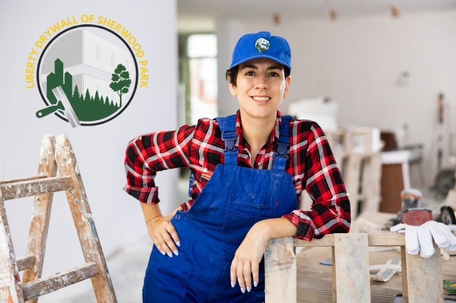 A drywall repair technician wearing a blue cap, plaid shirt, and overalls poses confidently in a residential renovation space. She leans against a wooden ladder with construction materials and tools in the background near Sunnydale Rd, and 89 St, Morinville, AB.