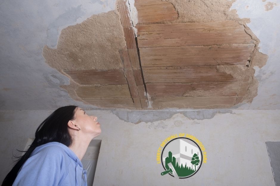 A woman examines a water-damaged drywall ceiling with exposed lath in her Sherwood Park, AB home.