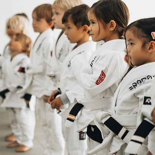 group of young students with white belts standing in line ready to start class