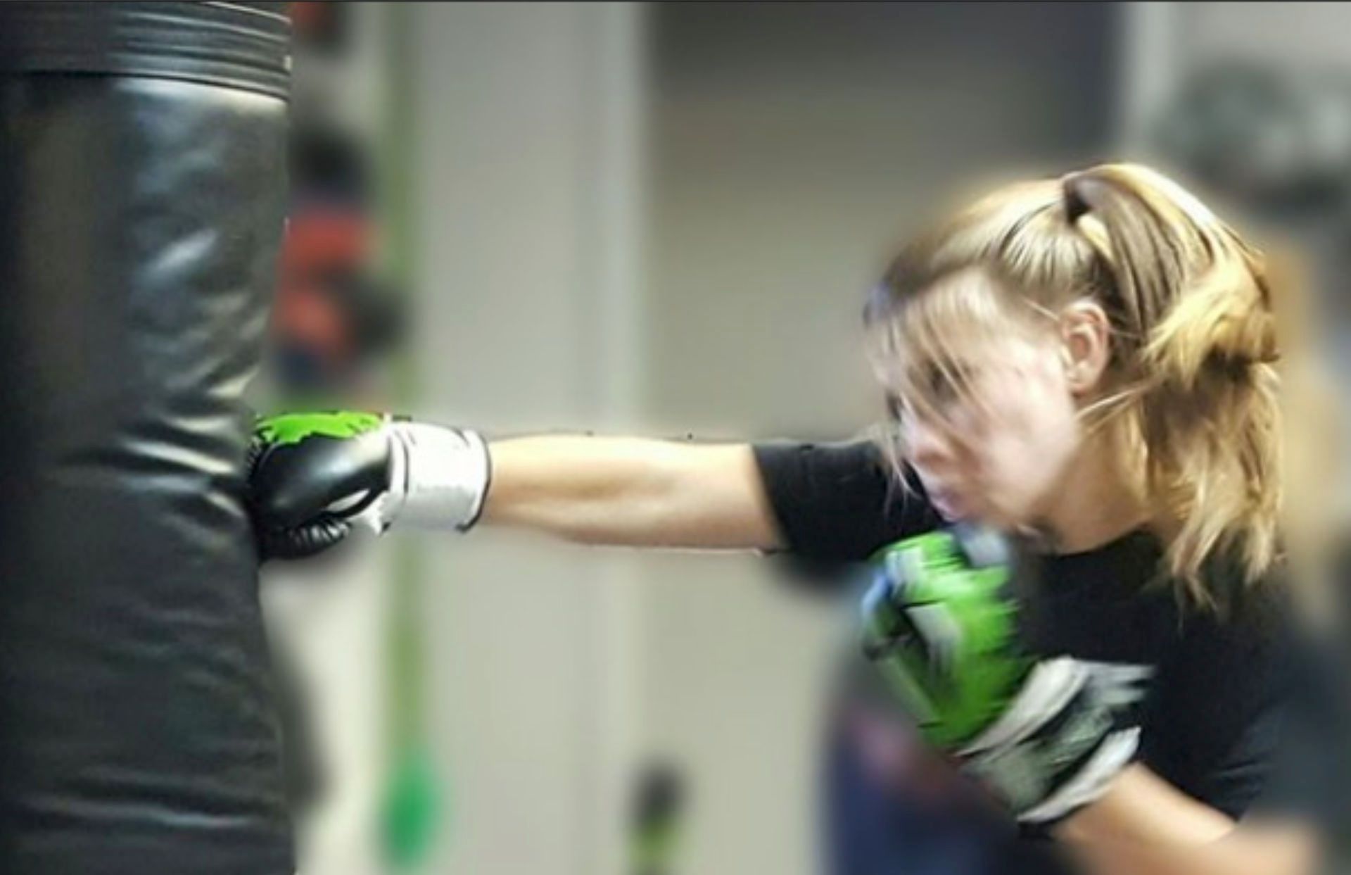 young student throwing a cross punch at the standing bags in class with gloves on