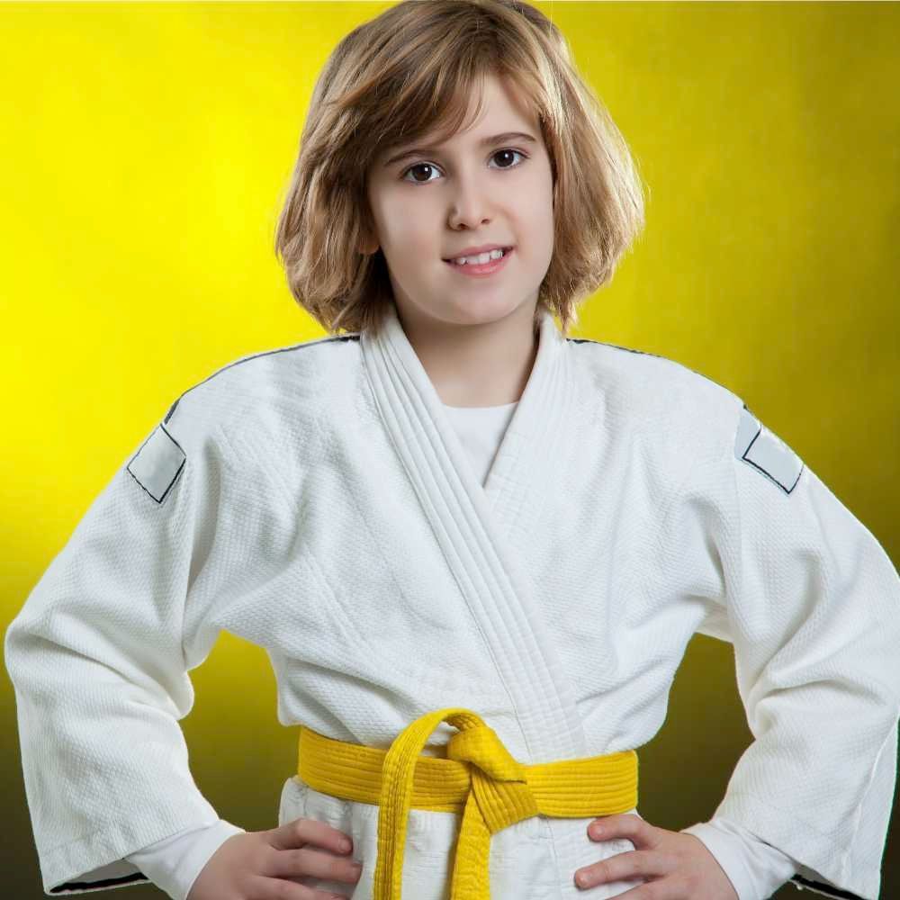 girl student in martial arts class posing in with new yellow belt