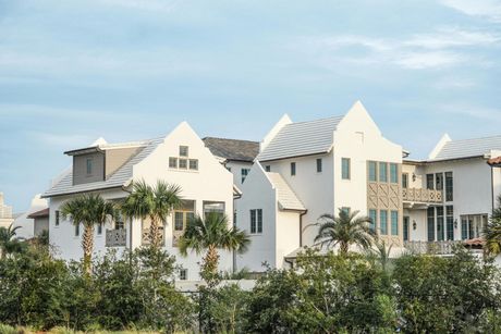 White buildings with gabled roofs, palm trees, and a blue sky, possibly a coastal community.