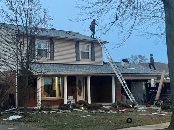 Two men are working on the roof of a house.