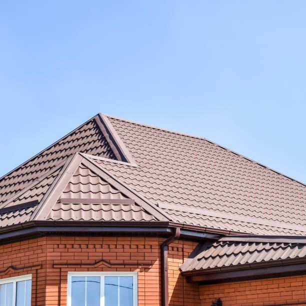 Brown metal roof on a brick building against a blue sky.