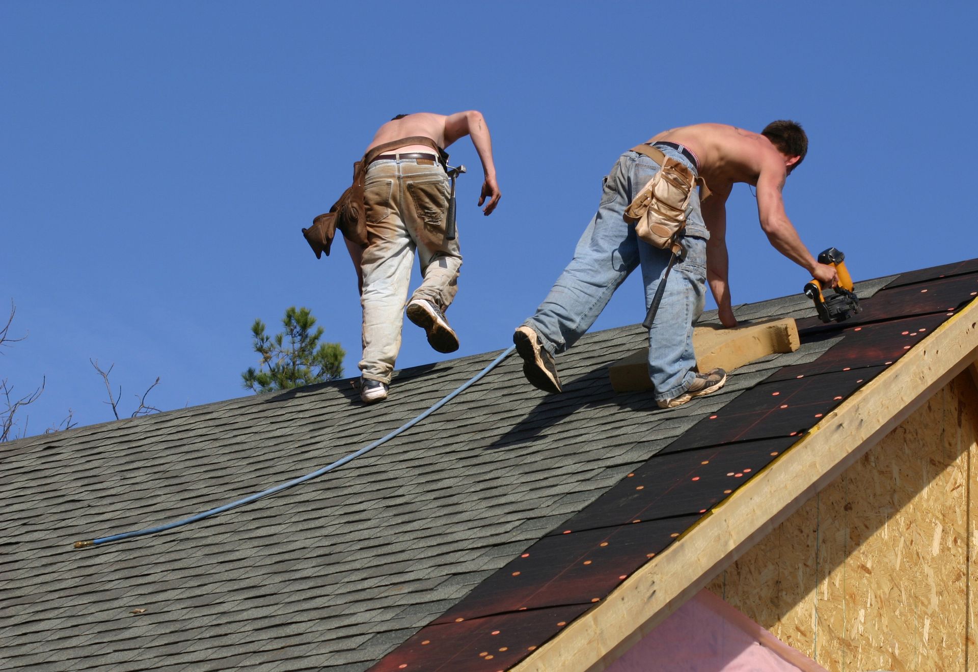 Two men performing roof repairs with tools, showcasing a professional roof repair contractor team.