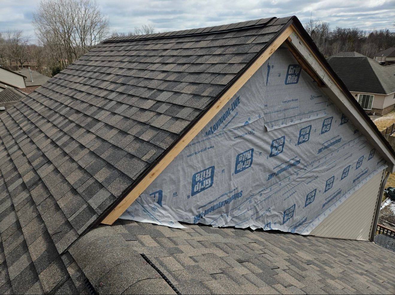 The roof of a house is being covered with a roofing material.