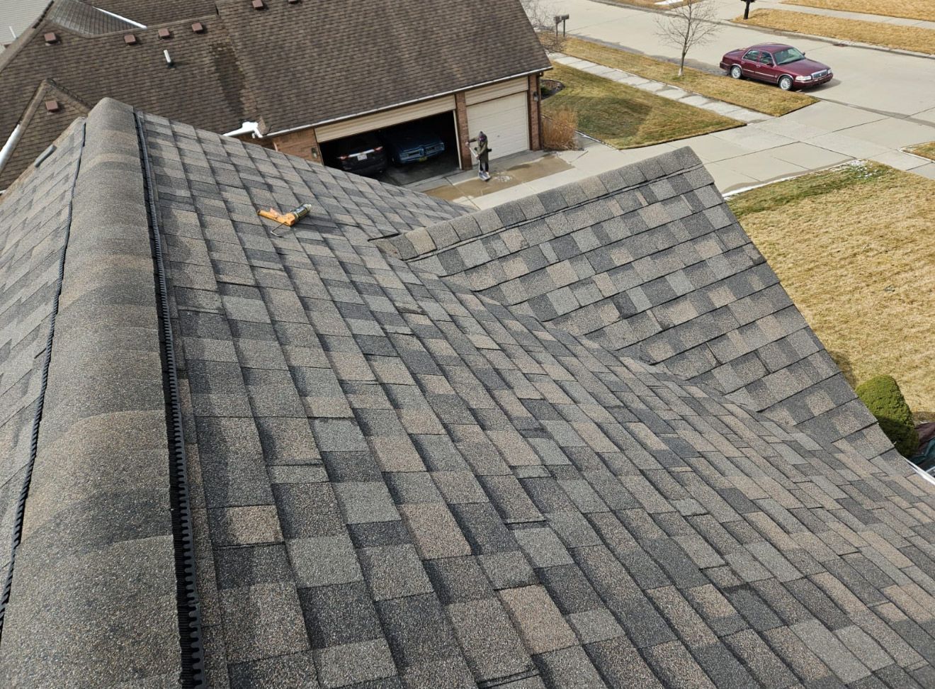 An aerial view of a roof of a house with a car parked in the driveway.