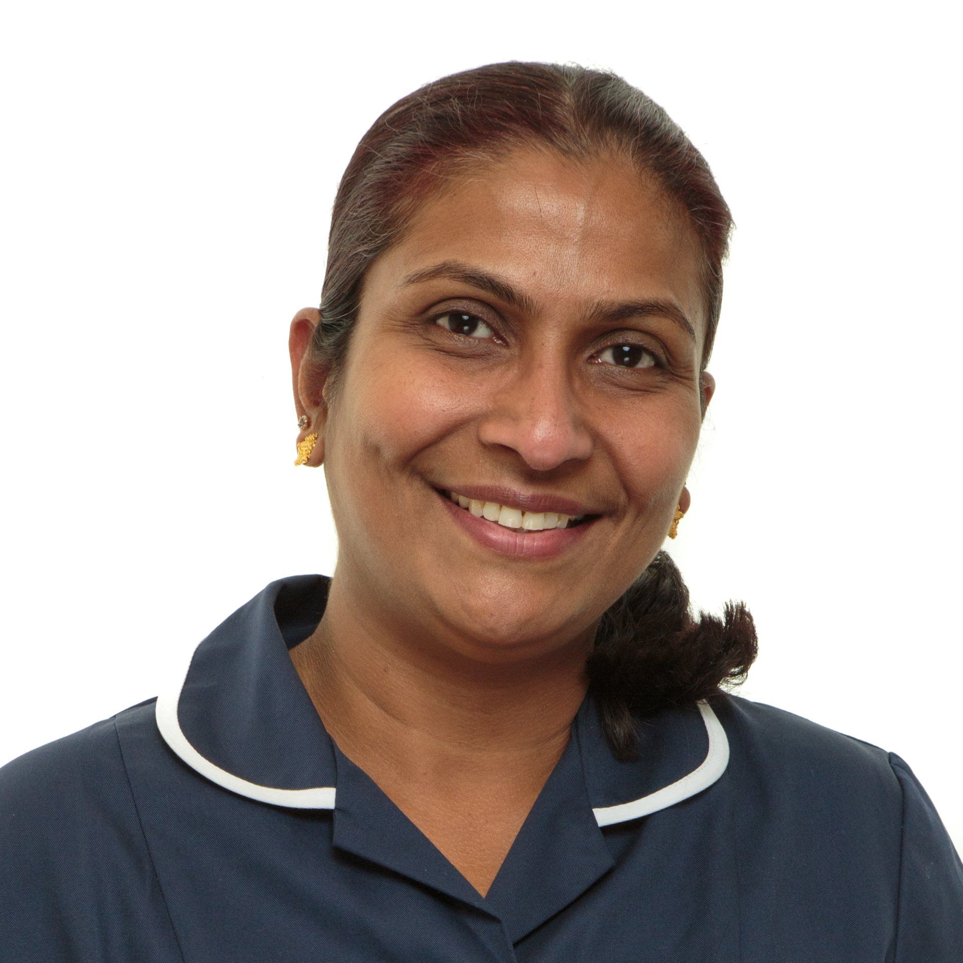 Professional team headshot in London of an Indian nurse wearing uniform, smiling and stood against a white background