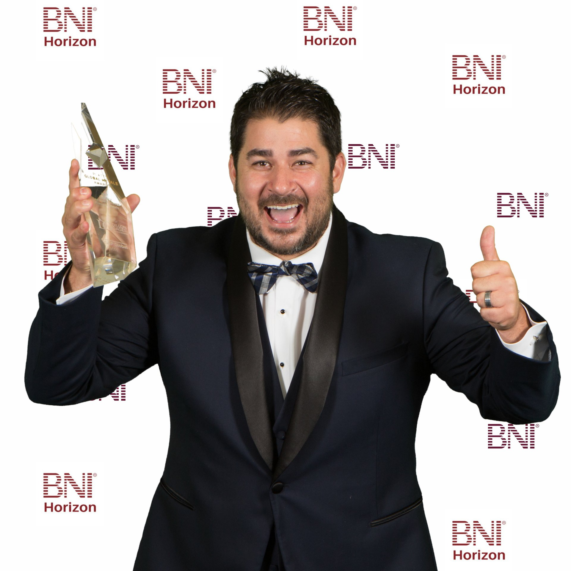 Man holding an award trophy in front of a green screen backdrop