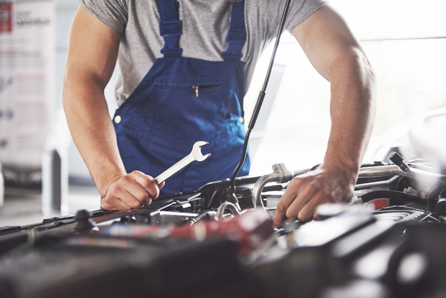 A man is working on a car engine with a wrench.