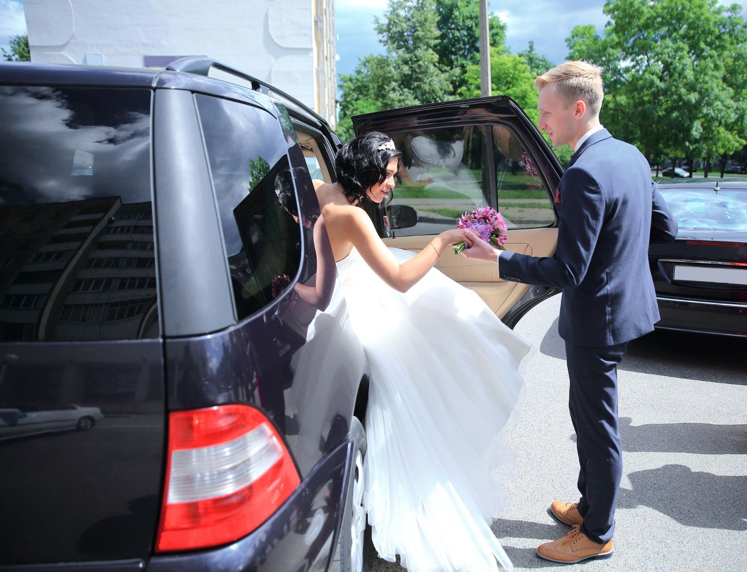 A bride and groom are getting out of a car