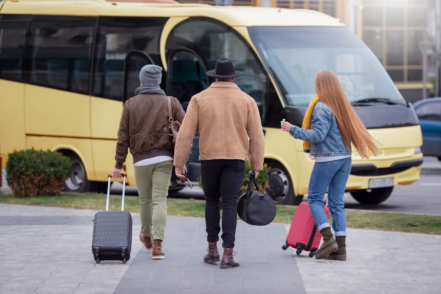 A group of people are walking towards a bus with luggage.