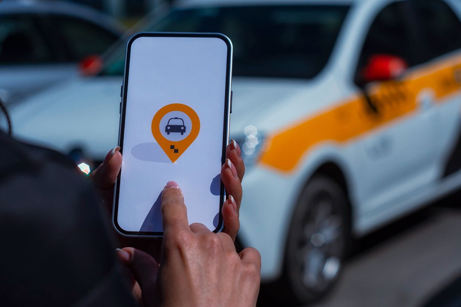 A person is holding a cell phone in front of a car.
