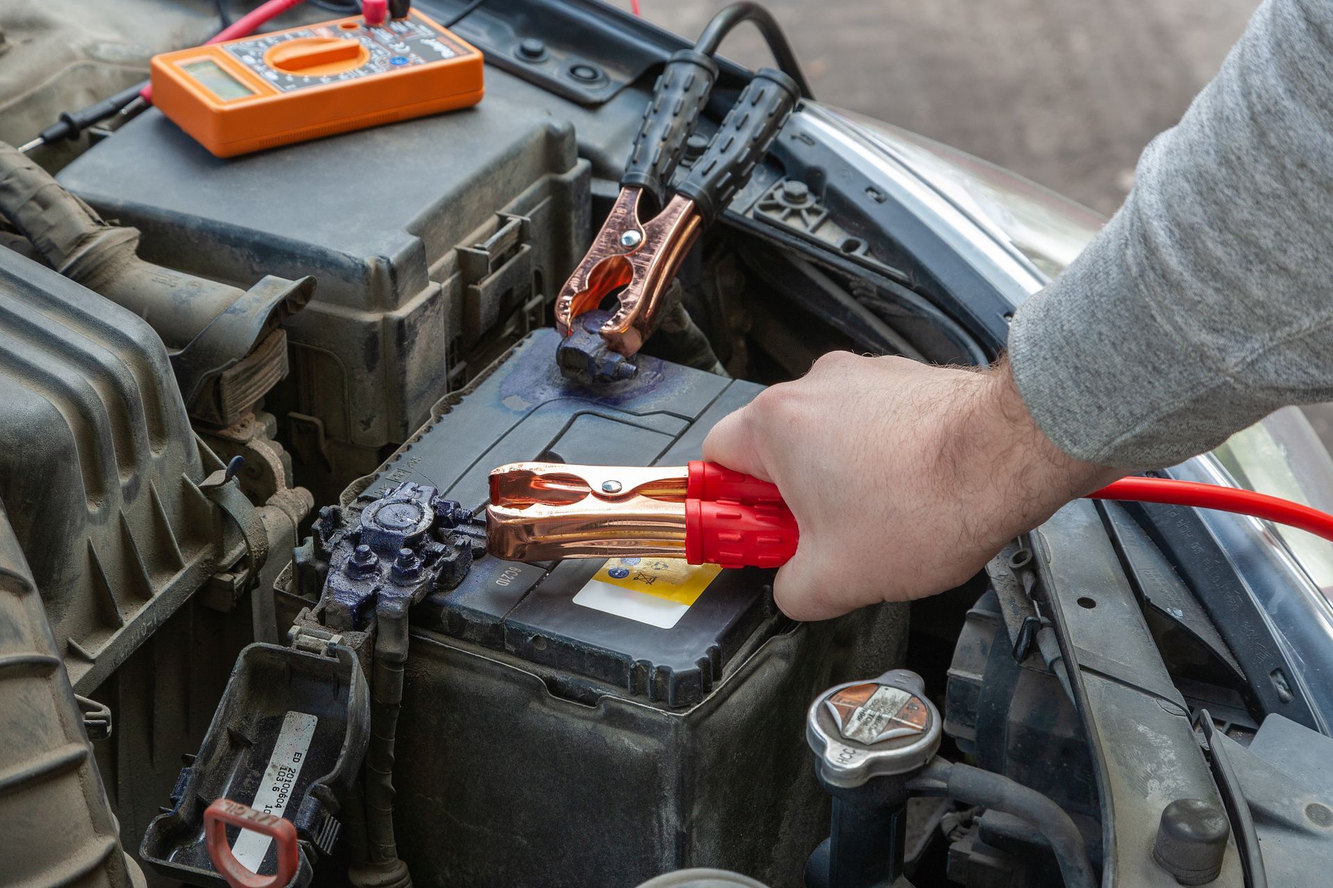 A person is charging a car battery with jumper cables.