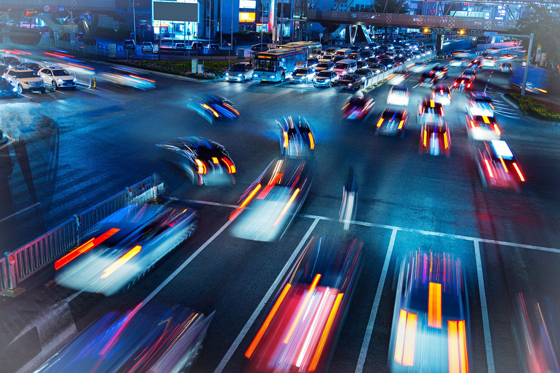 Ein verschwommenes Bild einer belebten Kreuzung bei Nacht, auf der Autos entlangfahren.