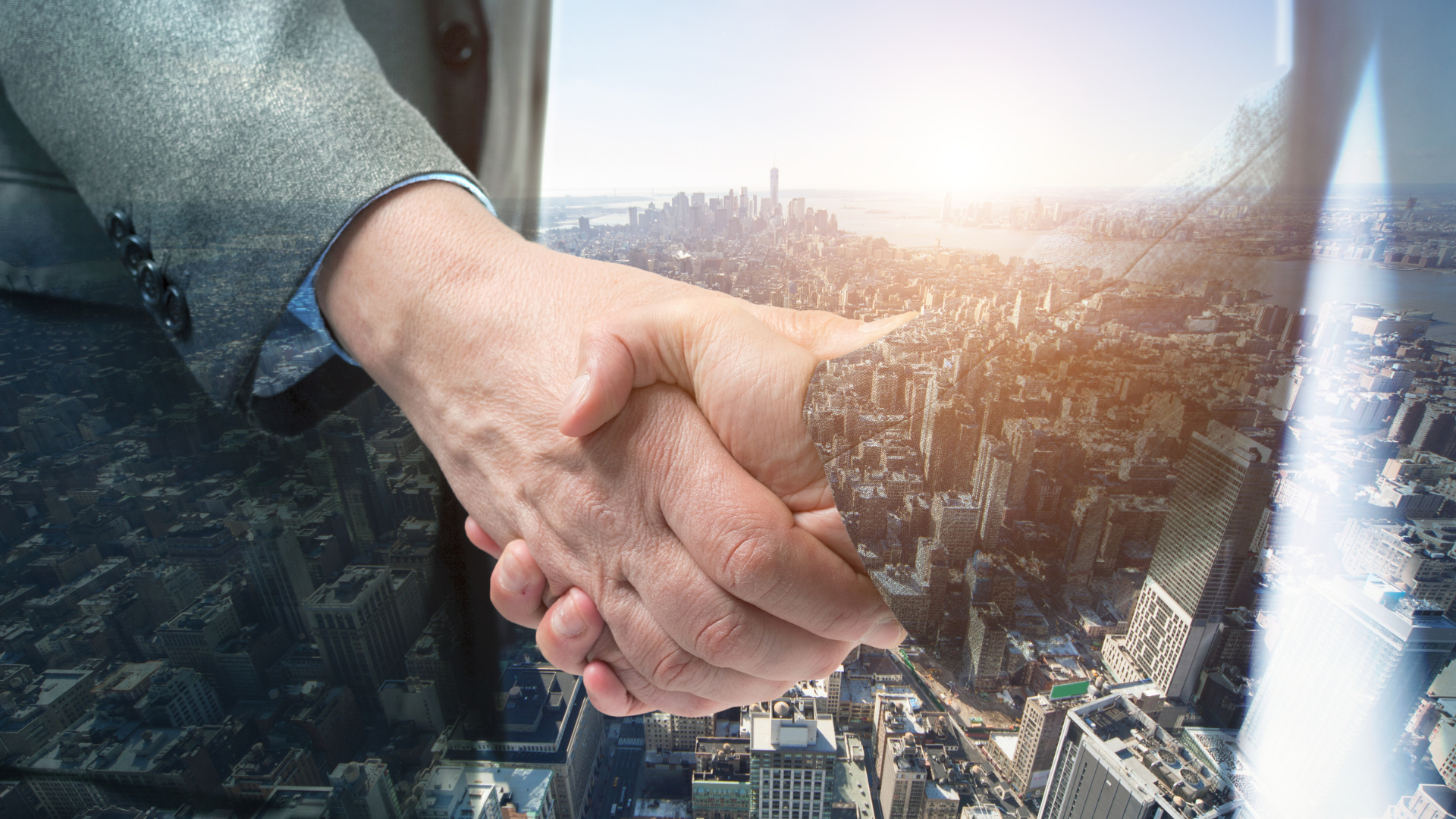 A close up of two people shaking hands with a city in the background.