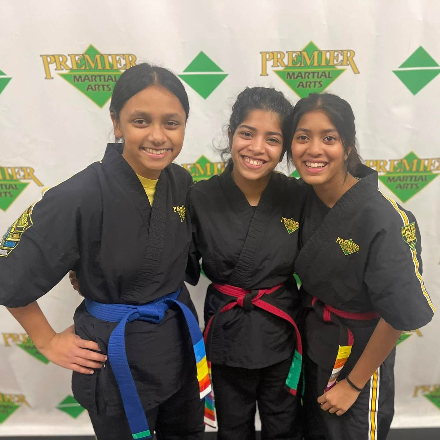 A man is kneeling down next to a young boy in a taekwondo class.