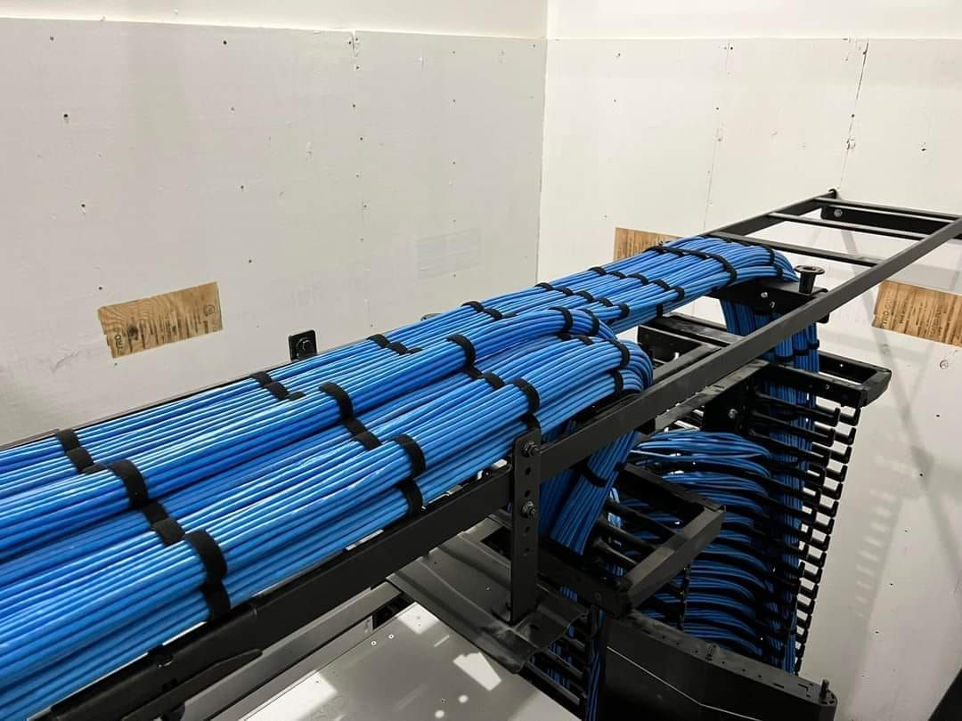 A bunch of blue wires are stacked on top of each other on a server rack.