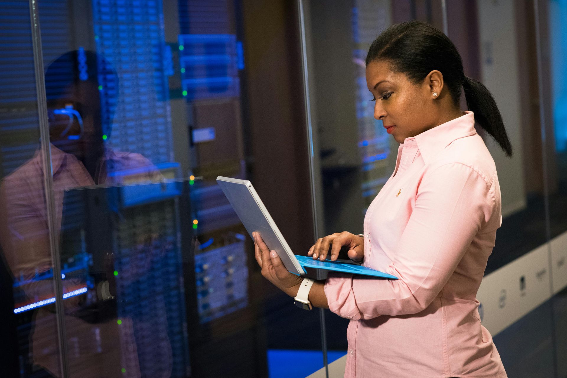A woman is using a laptop computer in a server room.