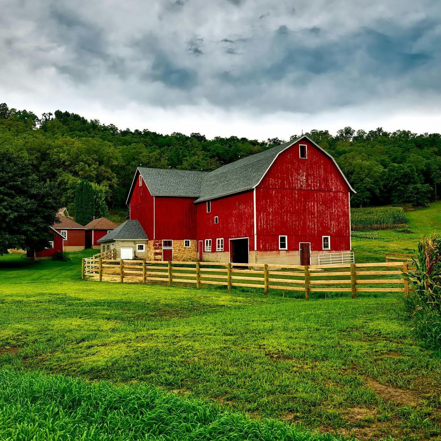 A red barn with a wooden fence in front of it