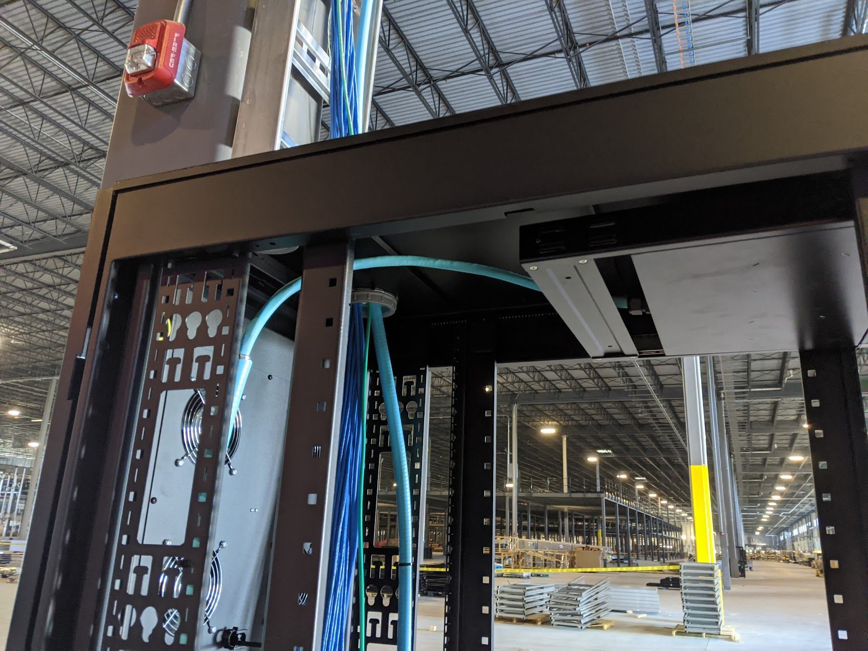 A server rack with a lot of wires coming out of it in a warehouse.
