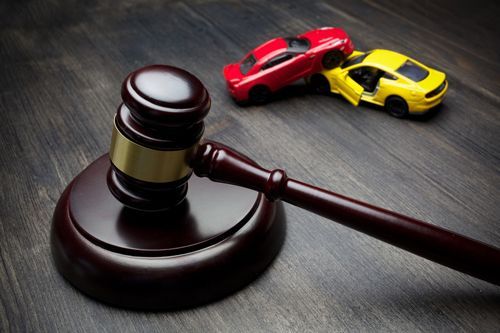 Gavel on a desk with toy cars in a crash, symbolizing a car accident attorney in Casper, WY at Chapman Valdez & Lansing.