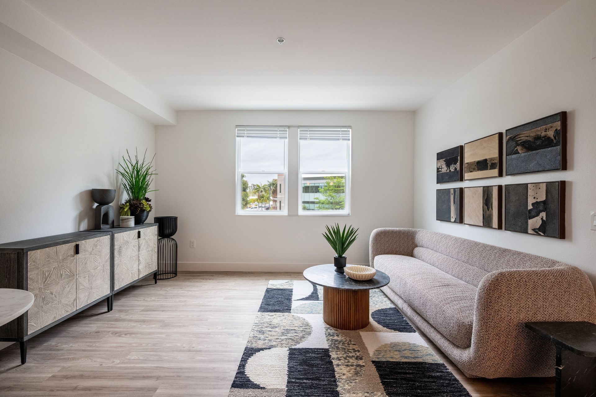 A living room with a couch , table , and two windows.
