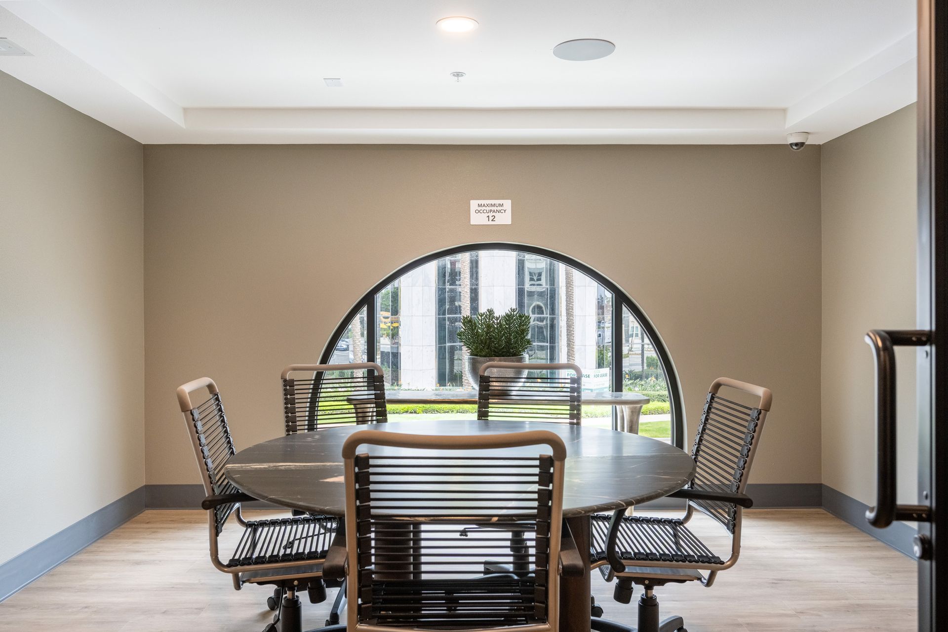 A conference room with a round table and chairs and a window.