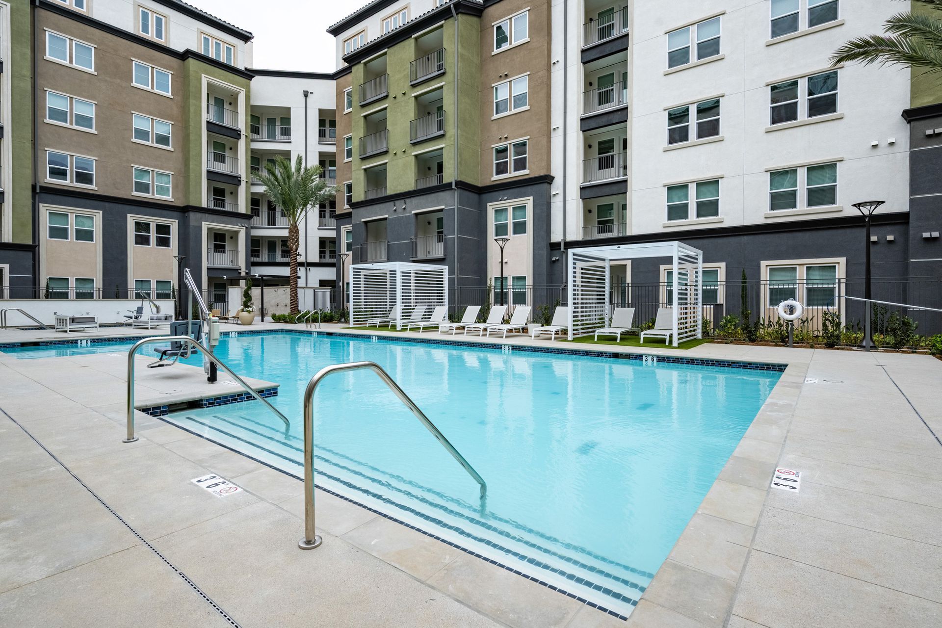 A large swimming pool in front of a building with stairs leading to it.
