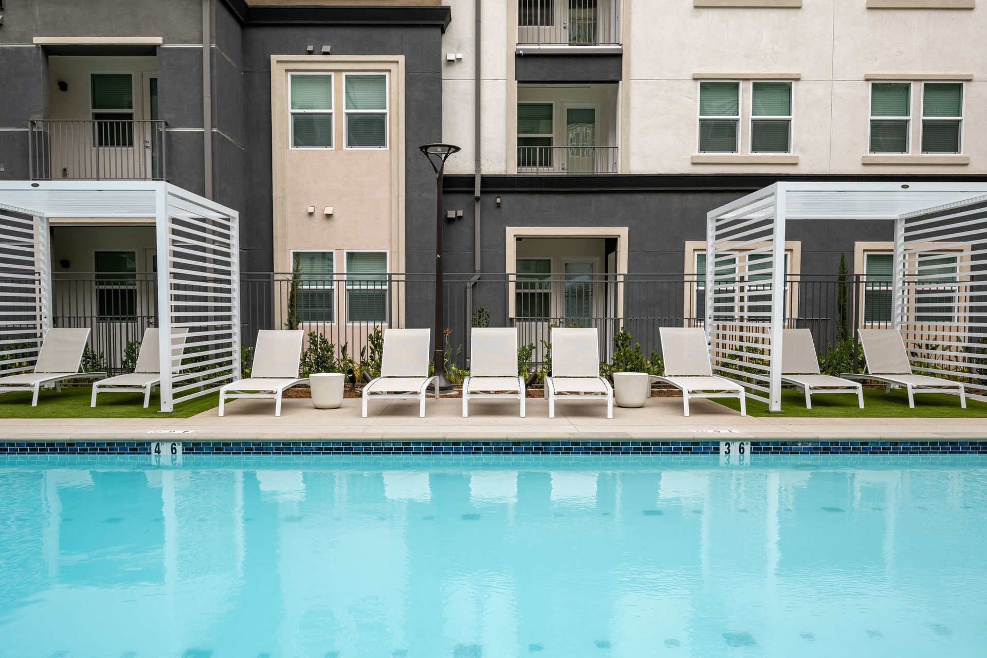 A large swimming pool surrounded by lounge chairs in front of a building.