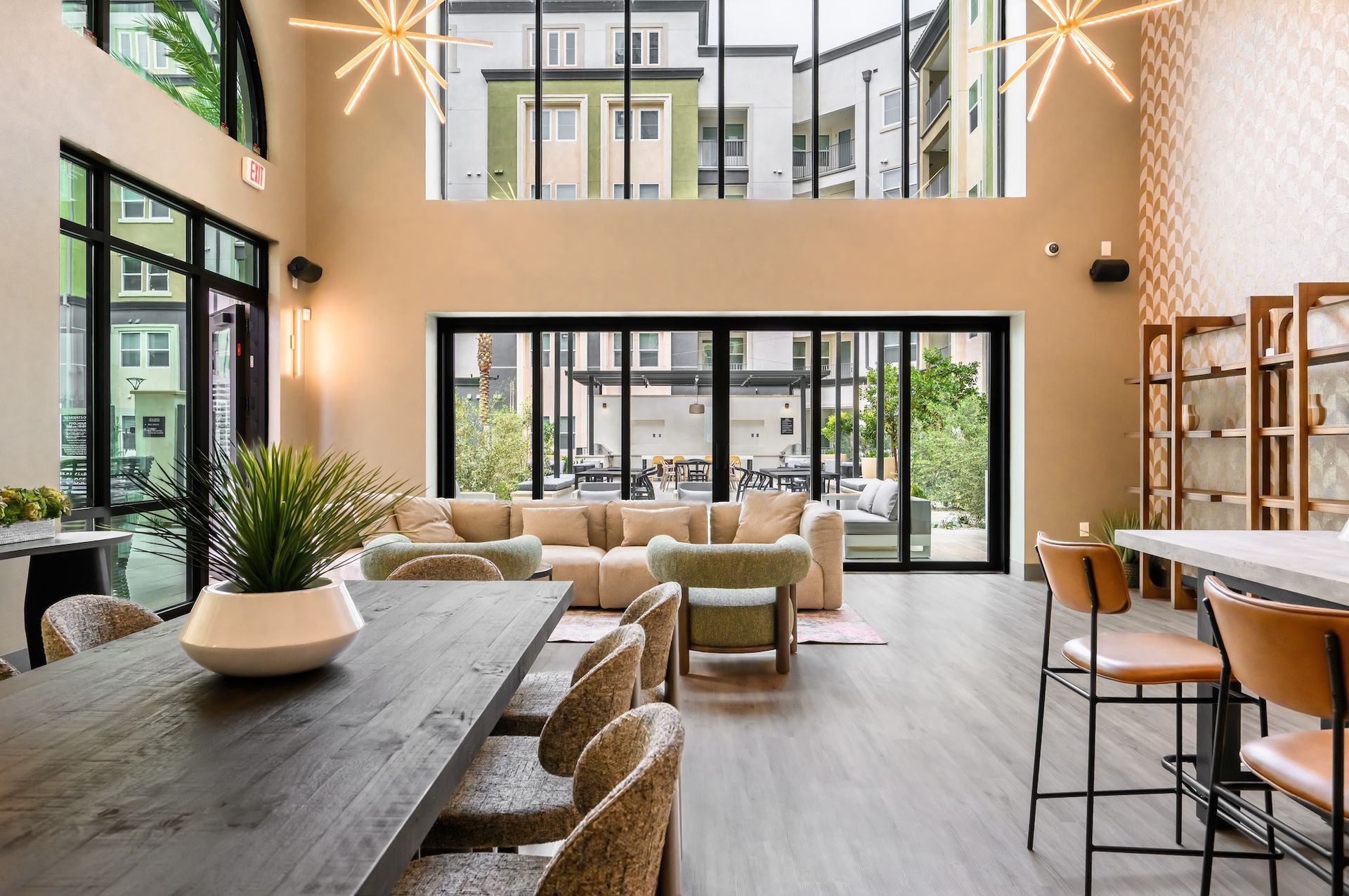 Spacious, modern lounge with floor-to-ceiling windows, couches, a dining table, and bar seating overlooking an outdoor patio.