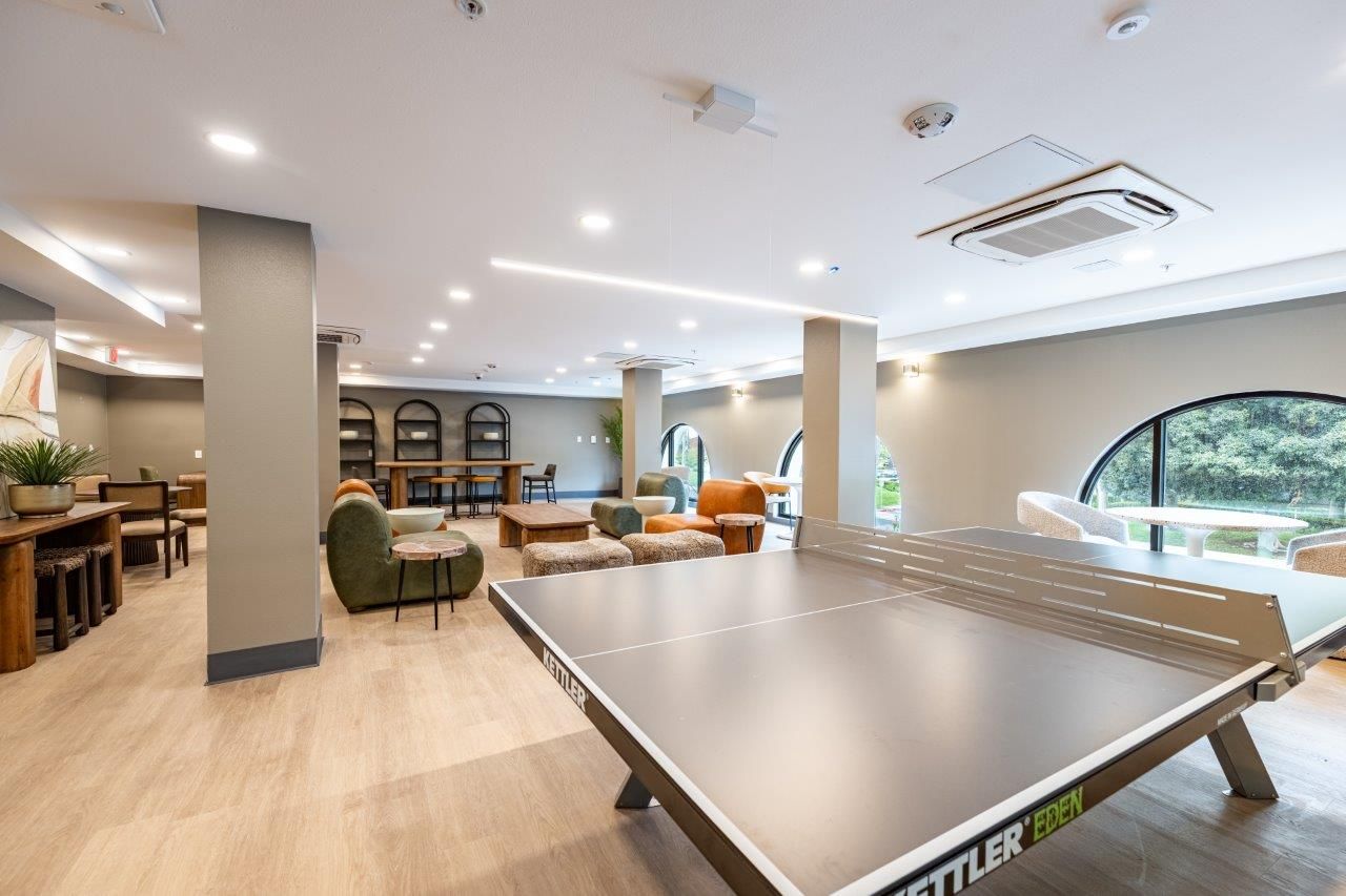 A modern, light-filled recreational room with a ping pong table at The ENZO