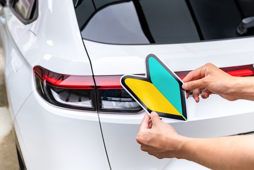 A Person Is Putting A Sticker On The Back Of A Car — JW Signs and Designs In Mount Isa, QLD