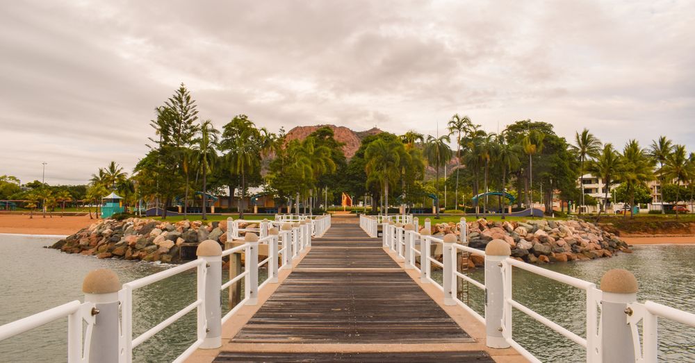 A Wooden Dock Leading To A Beach With A White Railing — JW Signs and Designs In Townsville, QLD