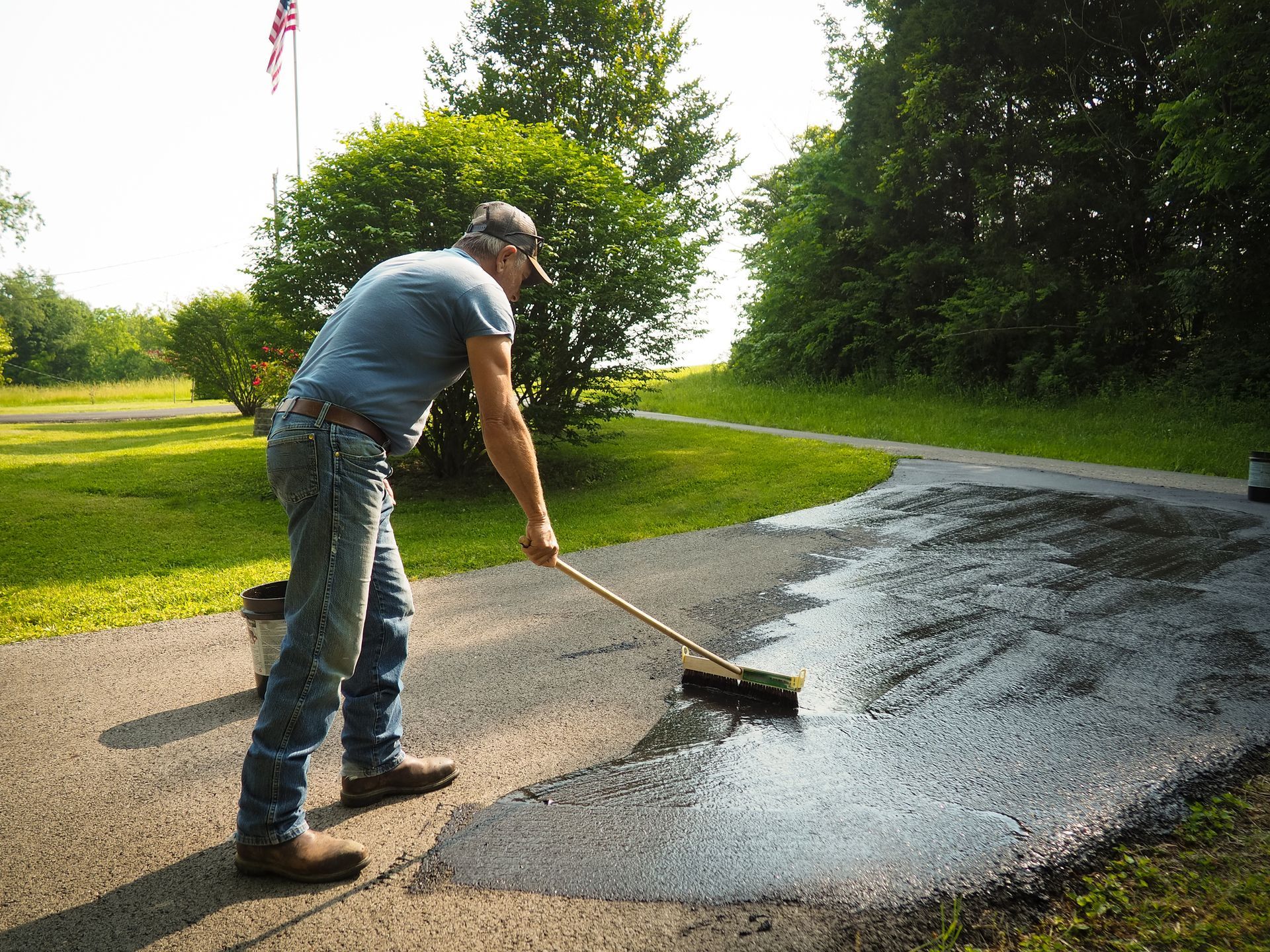 Man sealing driveway with squeegee tool during asphalt maintenance work Man sealing driveway with squeegee tool during asphalt maintenance work