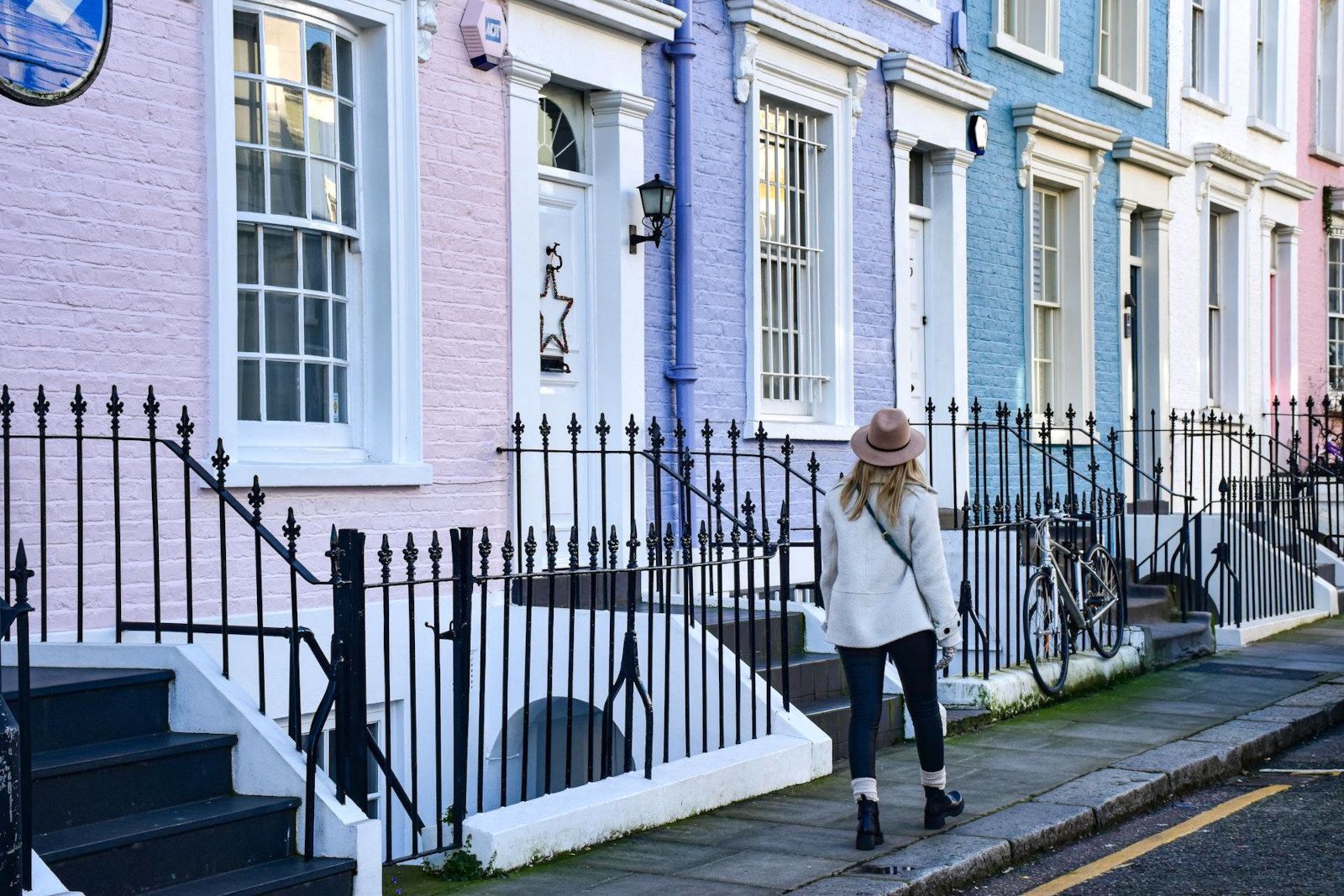 A woman is walking down a sidewalk in front of a row of colorful houses.