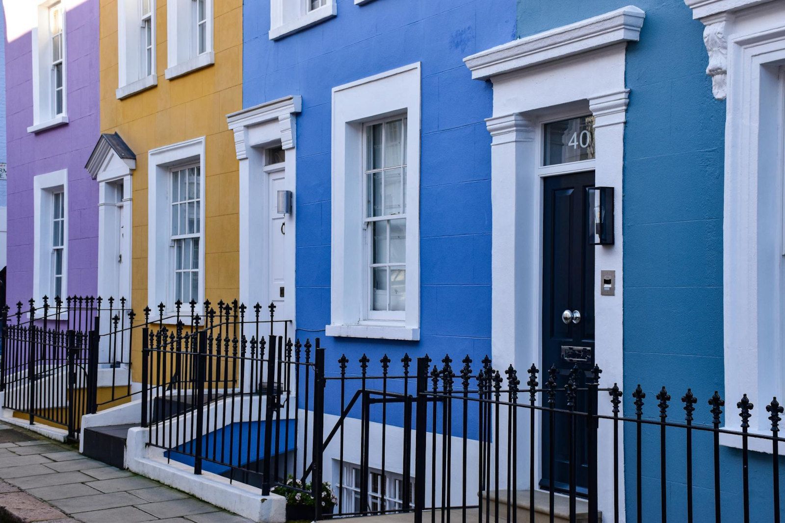 A row of colorful houses with a black fence in front of them.