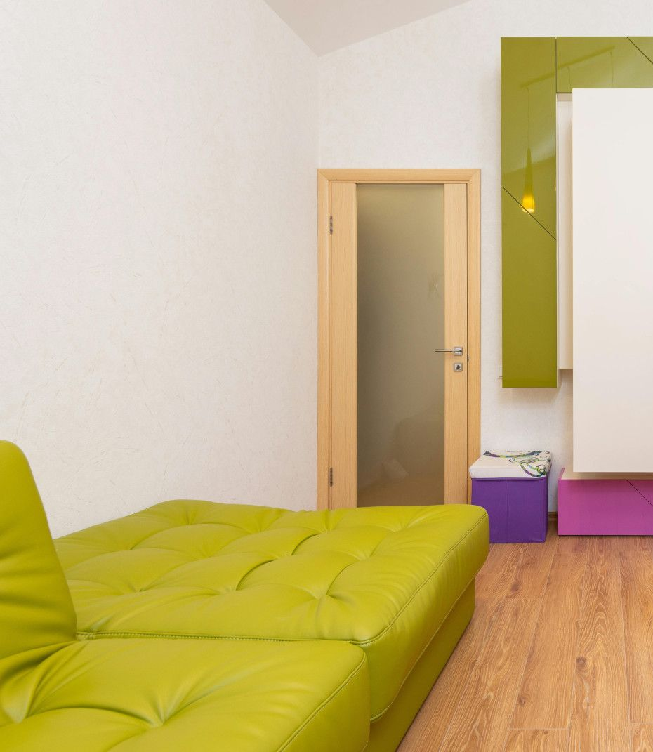 Lime green couch in a room with a light wood door and a green and white wall unit.