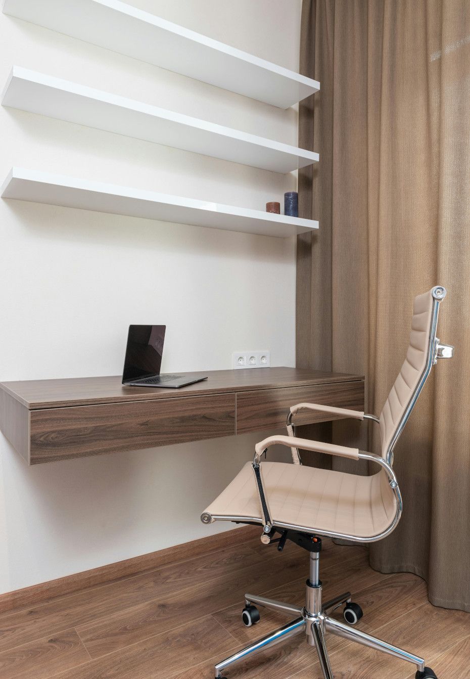 Home office with floating desk, chair, and shelves on a neutral-colored wall.