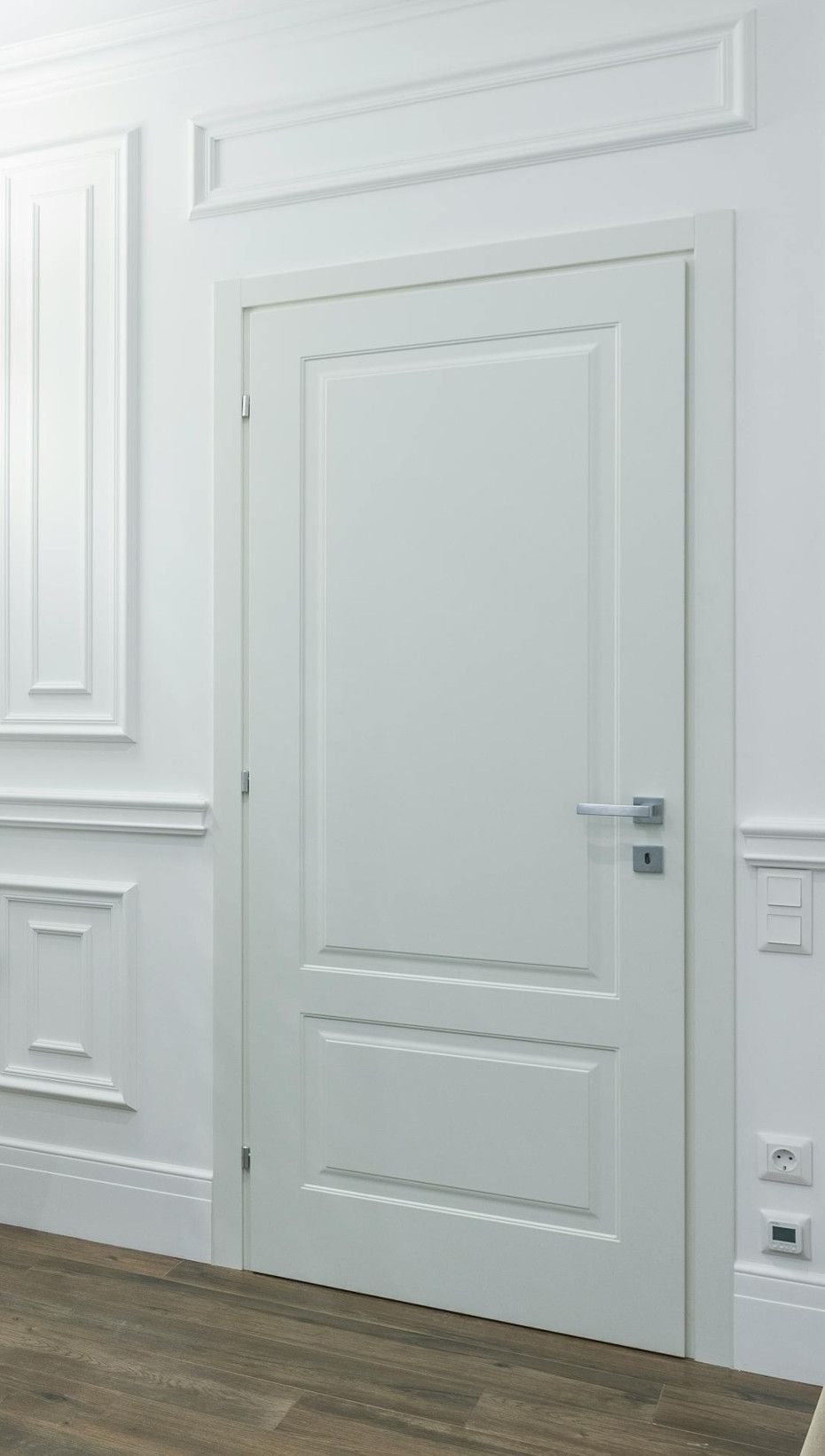 White interior door with decorative molding and silver handle.
