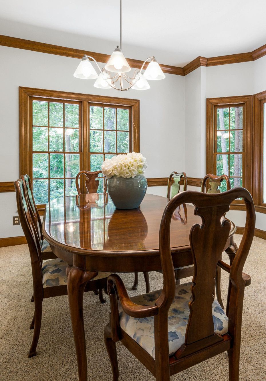 Formal dining room with wood trim, windows, a table set for six, and a chandelier.