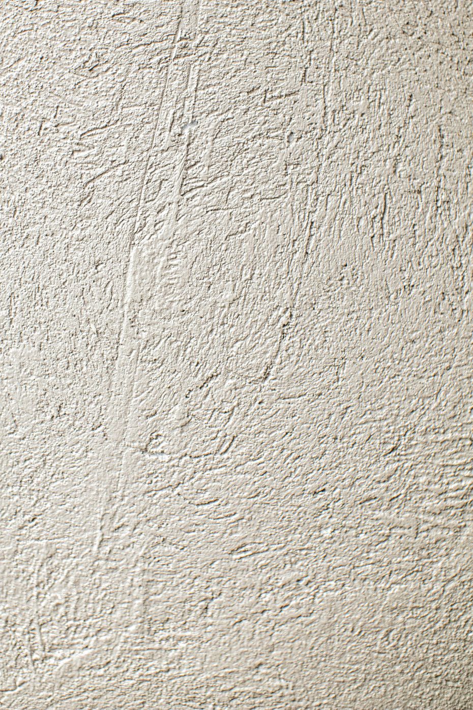 Close-up of a rough, textured wall with a light gray color. Several scratches are visible.
