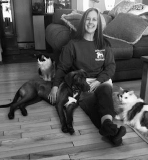 A woman is sitting on a couch with a dog and a cat