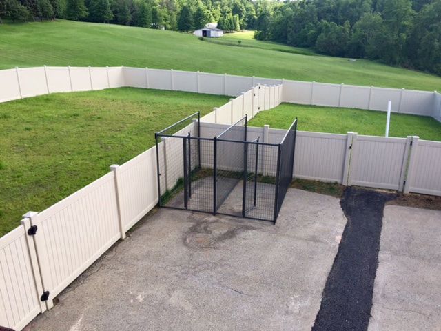 A white fence surrounds a large grassy field
