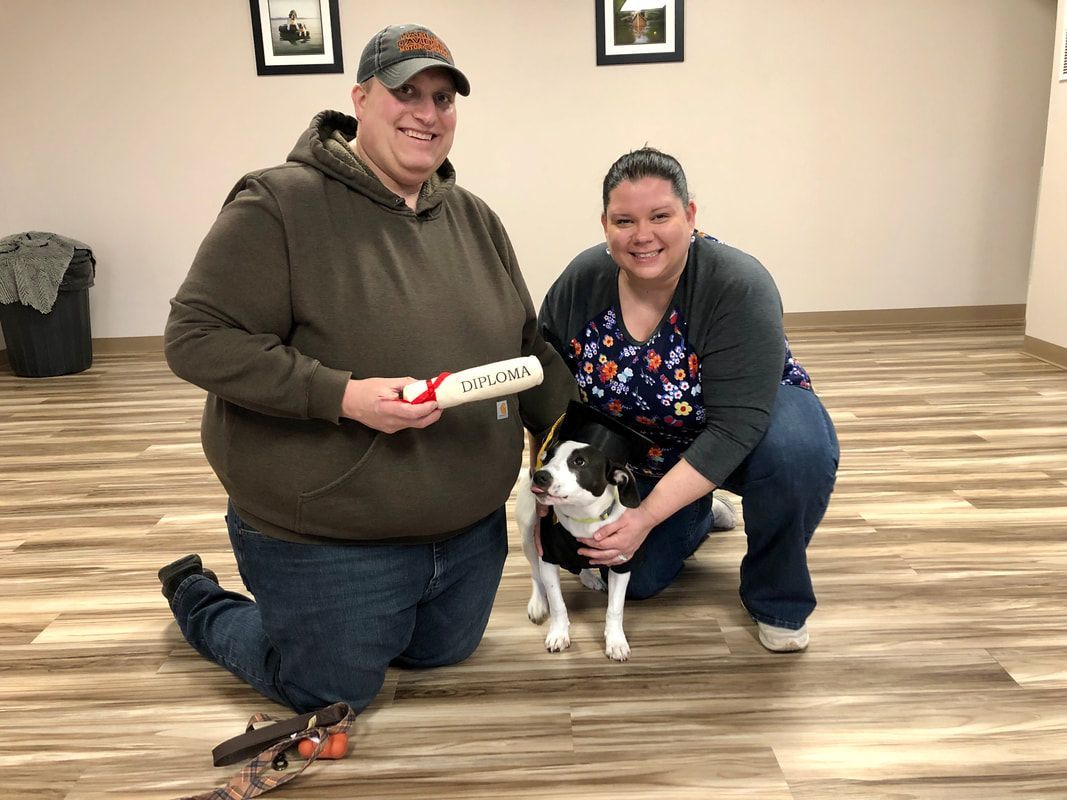 A man and a woman are kneeling down next to a dog.
