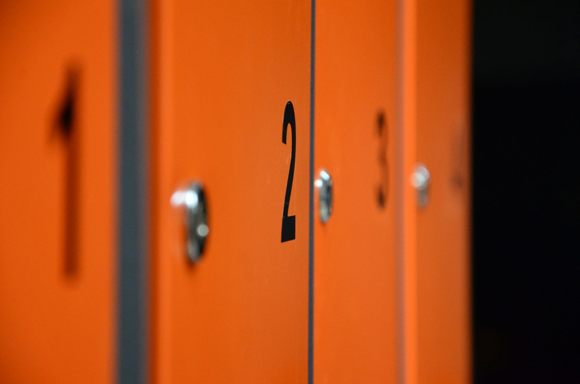 Orange lockers with black numbers 1, 2, 3, and 4. Close-up view with shallow depth of field.
