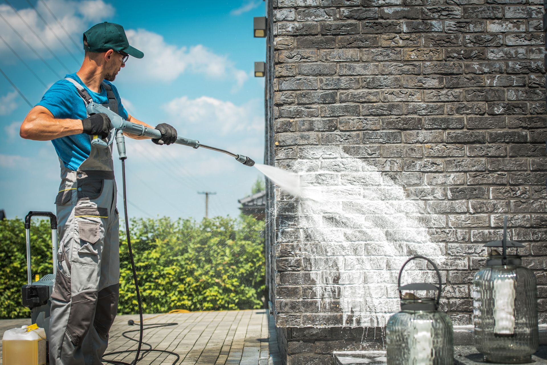 A man is cleaning a brick wall with a high pressure washer.