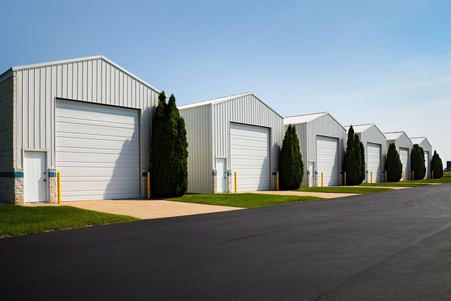 A row of white warehouses with trees in front of them