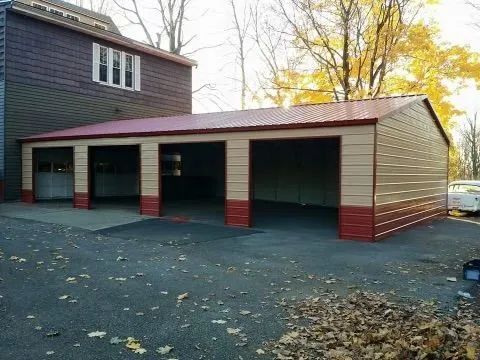 A garage with a red roof is next to a house.